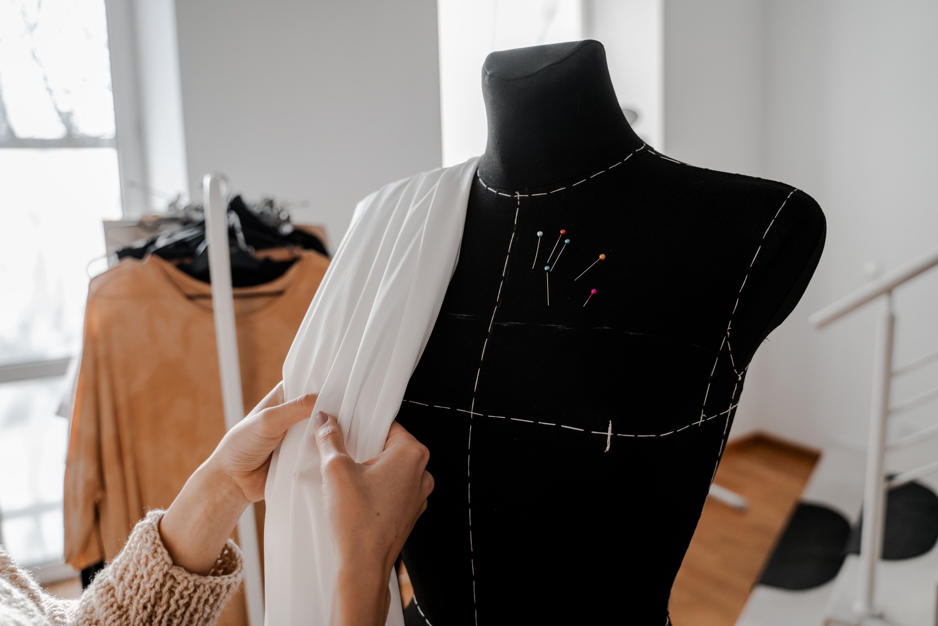 Hands that sort through the fabric. Mannequin with fabric on the shoulder and stuck pins into the fabric in design studio for sewing and tailoring, special education conceptHands that sort through the fabric. Mannequin with fabric on the shoulder and stuc